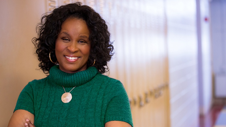 A person smiling in a green sweaterAI-generated content may be incorrect.